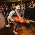 Bruidegom danst met zijn oma tijdens het trouwfeest, waarbij oma vrolijk in de lucht springt met haar voeten van de vloer